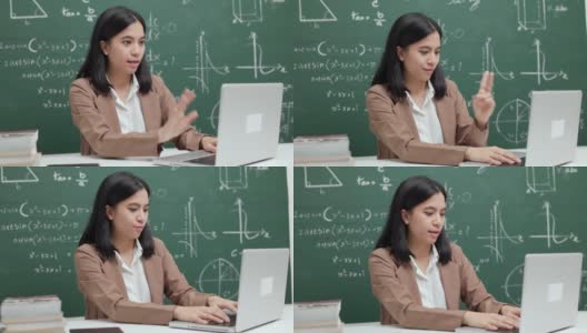 年轻的亚洲女教师坐在用笔记本电脑与学生视频会议。女教师在课堂上通过计算机在线课程直播进行数学培训。高清在线视频素材下载