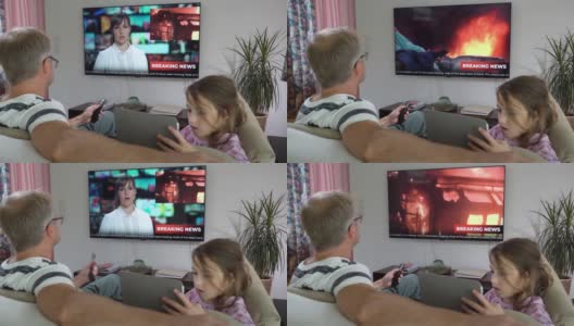 一位中年男子带着他的小女儿坐在电视机前高清在线视频素材下载