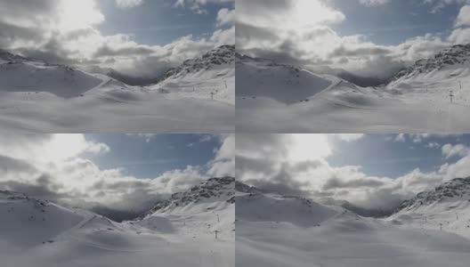 在冬天，蜿蜒的小路穿过被雪覆盖的山峰，阳光透过云层在蓝天中窥视高清在线视频素材下载