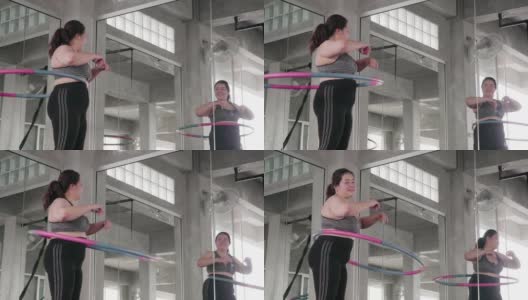 一个超重的年轻女子正在用呼啦圈锻炼高清在线视频素材下载
