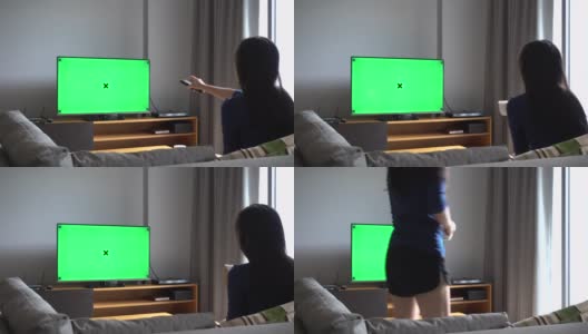亚洲妇女看电视与绿色屏幕，拍摄背后的模特肩膀高清在线视频素材下载