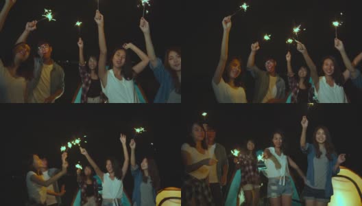 4K超高清慢动作:一群亚洲朋友在夏天的海滩露营庆祝与烟花灯在晚上。每个人都在快乐的跳舞，户外活动或度假。高清在线视频素材下载