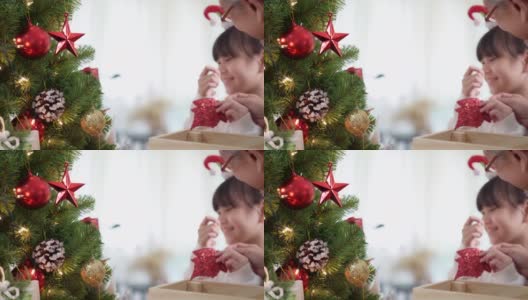 快乐的亚洲女孩和她的祖父几世同堂装饰圣诞树一起准备快乐的节日冬天。高清在线视频素材下载