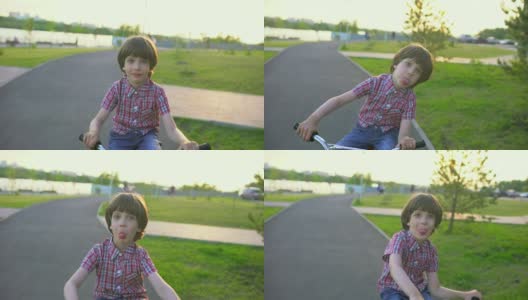 在夏日阳光明媚的夕阳下，一个小男孩在马路上骑自行车。快乐的男孩骑着自行车，在户外享受大自然的乐趣。积极运动快乐家庭休闲度假。慢动作高清在线视频素材下载
