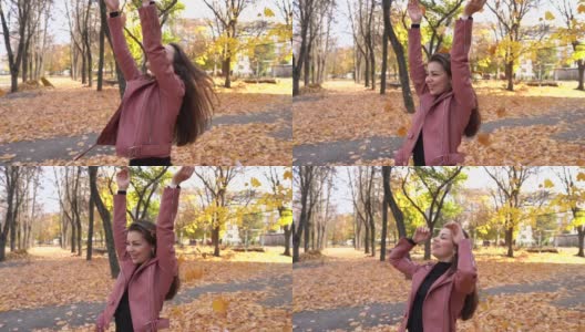 年轻女子在秋天的公园里抛起枯叶，快乐少女高清在线视频素材下载