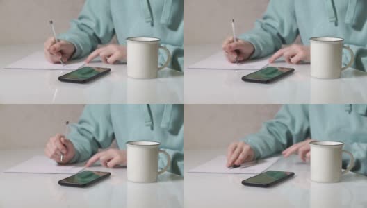 这个女孩用钢笔在纸上写字。把钢笔放在桌子上。从桌子上站起来离开。家的气氛。居家办公前视图。高清在线视频素材下载