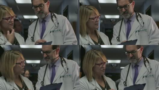 两名医生在繁忙的诊所或医院的走廊上交谈高清在线视频素材下载
