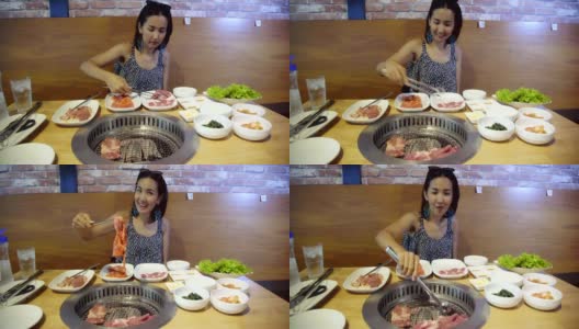 年轻美丽的亚洲女人烧烤烧烤在韩国锅。特写猪肉片在韩国餐厅烤。高清在线视频素材下载