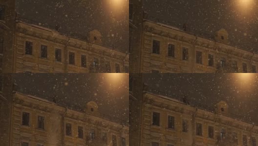 人从屋顶上飘落雪。晚上城里下大雪高清在线视频素材下载