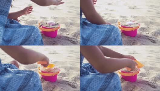 一个小女孩在沙滩上用铲子和水桶玩沙子高清在线视频素材下载