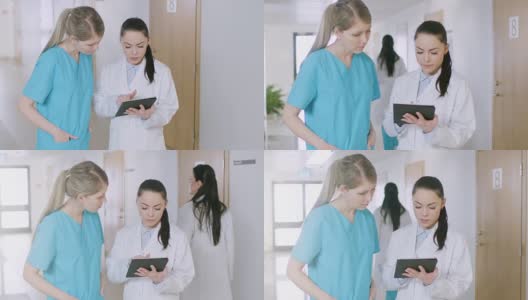 在医院里，忙碌的医生在走廊里一边聊天一边使用平板电脑。新型现代化、功能齐全的医疗设施。高清在线视频素材下载