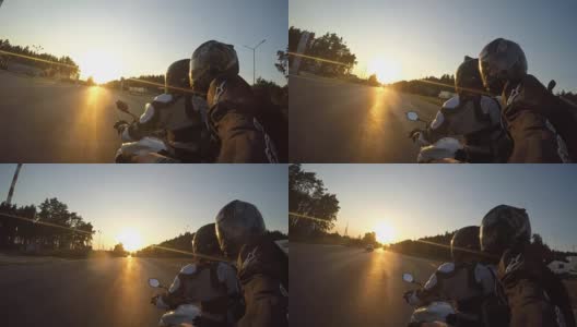 日落时分，两名男子骑着摩托车高速行驶在乡村公路上。朋友们骑着自行车向太阳高速前进，自拍。观点关闭高清在线视频素材下载