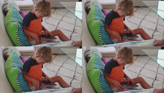 孩子在平板电脑上玩游戏。小男孩在家里使用电子设备高清在线视频素材下载