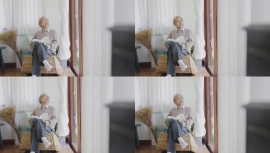 早上，退休的灰白头发的亚洲人爷爷坐在客厅看书，在家中自我隔离隔离。隔离或封锁期间在家活动的生活方式。高清在线视频素材下载