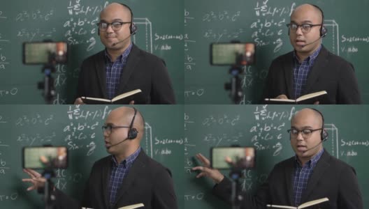 印度年轻教师男子戴着耳机通过智能手机进行在线视频会议直播。亚洲数学教师在线授课，供学生在线学习。高清在线视频素材下载