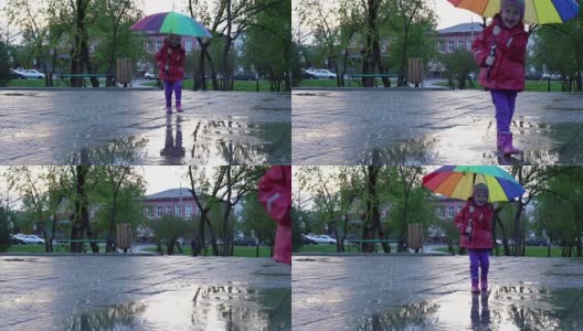 可爱的小女孩拿着五颜六色的雨伞在夕阳下穿过公园的水坑高清在线视频素材下载