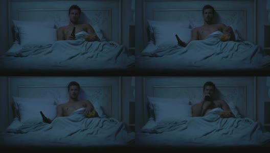 单身男性躺在床上，看电视，吃零食，慵懒的周末高清在线视频素材下载
