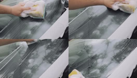 男人的手用海绵和泡沫擦洗汽车的挡风玻璃。汽车服务理念高清在线视频素材下载