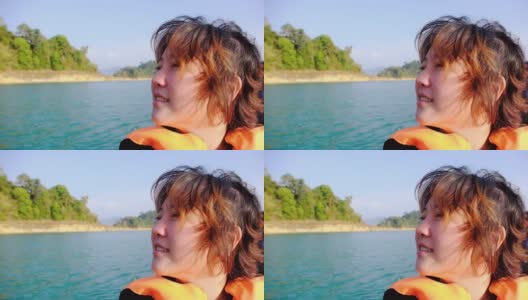 慢镜头，幸福年轻的亚洲女子穿着救生衣微笑着在长尾船上放松清新的风自然“周兰湖(拉恰帕坝)”泰国苏拉塔尼考索国家公园。高清在线视频素材下载
