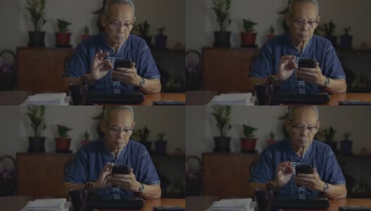亚洲高管晚上拿着现代智能手机在办公室发短信。老年商人使用有用的移动应用程序为企业管理组织。后期工作。高清在线视频素材下载