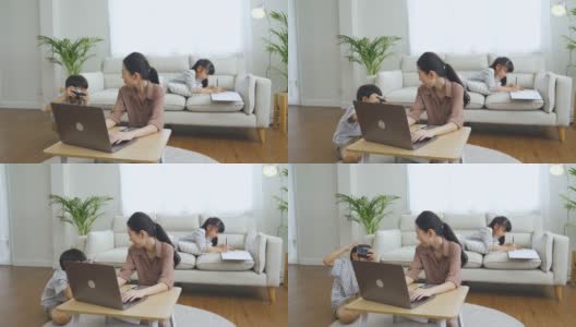 亚洲妈妈在笔记本电脑上工作，而她的孩子放松高清在线视频素材下载