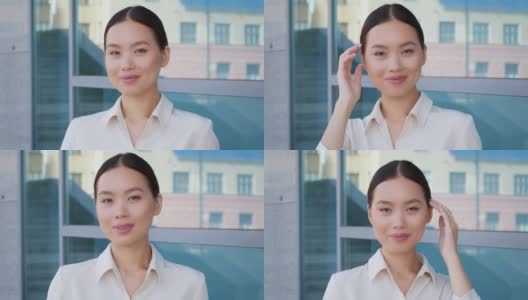 亚洲女商人对着镜头微笑，在现代建筑外摆姿势高清在线视频素材下载