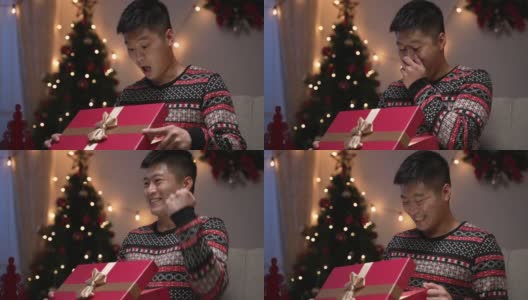 一名中国男子惊讶地捂着嘴，用“是”的手势庆祝，对自己在节日的家中得到的圣诞预设感到满意高清在线视频素材下载