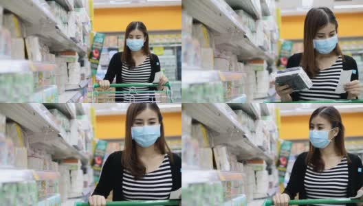 年轻的亚洲妇女带着防护口罩在超市购物，阅读清单高清在线视频素材下载