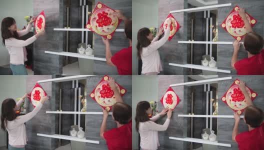 亚洲华人妇女和母亲在中国新年前夕用“财运”春联装饰她的客厅高清在线视频素材下载