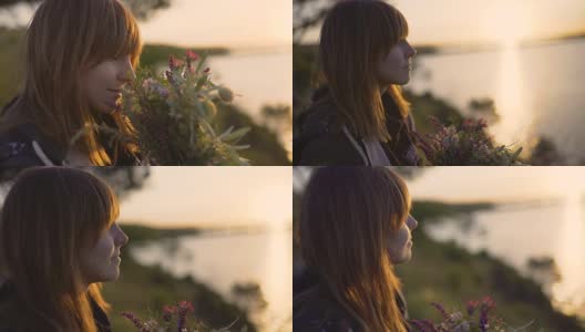 美丽的年轻女子拿着一束野花在日落的海岸上高清在线视频素材下载