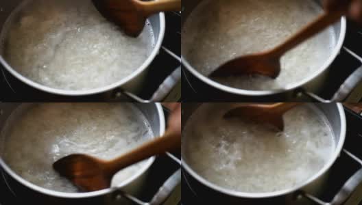 在不锈钢锅中加入开水，用木勺将米饭混合高清在线视频素材下载