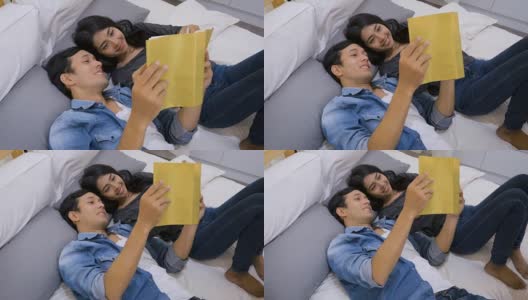 年轻的亚洲夫妇躺在家里的床上看书，爱的关系概念高清在线视频素材下载