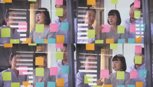 亚洲商务人士在办公室讨论新项目，年轻的女商人指着玻璃上的便利贴与她的同事在会议室，团队合作和会议概念高清在线视频素材下载