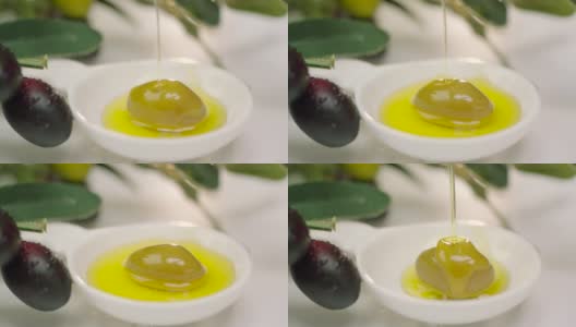 将橄榄油倒在白色碗里的绿橄榄上。高清在线视频素材下载