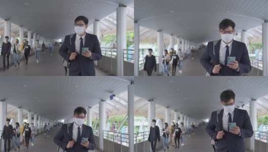 4K亚洲商务人士办公室人员走在城市火车站，使用智能手机和互联网为公司工作。商人戴口罩保护covid-19病毒大流行和空气污染。新标准的概念。高清在线视频素材下载