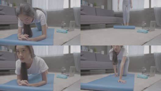 广角镜头。年轻的亚洲美女在平板支撑锻炼前在家里的客厅里滚动瑜伽垫。高清在线视频素材下载