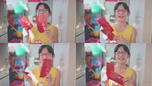 亚洲中国女孩看着手机摄像头，拿着红包和橘子向她的祖父母祝贺春节高清在线视频素材下载