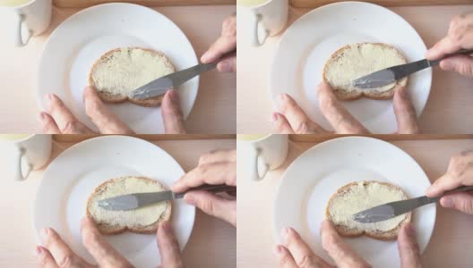 在面包上涂黄油。慢动作刀在面包表面涂黄油。特写镜头高清在线视频素材下载