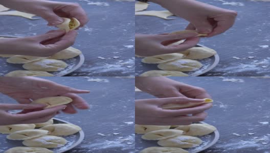 妇女的手用擀面杖擀平佩尔梅尼面团。无面筋食谱的传统俄罗斯菜肴在一个盘子。面粉木质表面，手工饺子高清在线视频素材下载