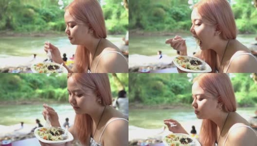 周末，年轻的亚洲女游客在海滨吃着辣木瓜沙拉高清在线视频素材下载