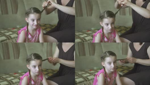 女人的手为她的小女儿做发型。一位妇女正在为她的女儿编头发。高清在线视频素材下载
