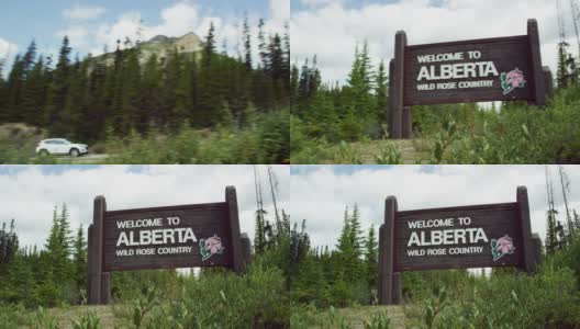 在一个多云的日子里，一辆汽车沿着美国/加拿大边境进入阿尔伯塔省，路边有“欢迎来到阿尔伯塔，野生玫瑰之乡”的标志高清在线视频素材下载
