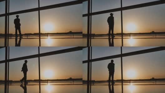 黄昏时分，一个游客站在机场的窗口观看飞机起飞的剪影。旅游理念，人在机场高清在线视频素材下载