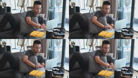 一个亚洲的中国少年男孩在家学习，在客厅用笔记本电脑高清在线视频素材下载