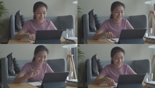 快乐的亚洲女性在家里的客厅里用平板电脑向在线家教挥手或打招呼。提出在家在线学习的概念高清在线视频素材下载