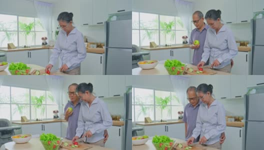 亚洲老年夫妇呆在家里，一起在厨房里消磨时间。浪漫坚强的老年人夫妇享受退休生活，在家里做饭。家庭活动关系高清在线视频素材下载