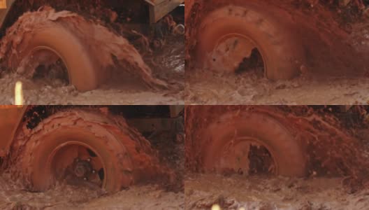 肮脏的越野车的巨大轮子卡在水坑和泥里，特写镜头。汽车在泥里打滑。越野驾驶的概念高清在线视频素材下载