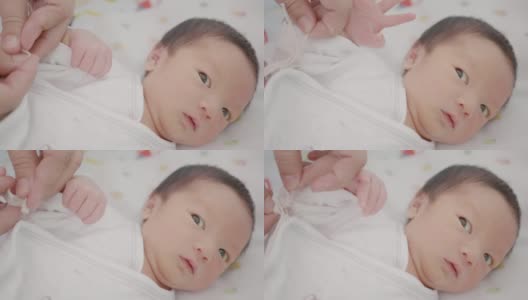 快乐的亚洲家庭母亲打扮新生婴儿(0-1个月)男婴。高清在线视频素材下载