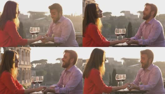 夕阳西下，浪漫优雅的情侣坐在罗马斗牛场前的餐厅桌前，手握红酒谈心高清在线视频素材下载