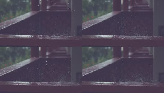 慢动作:小雨滴落在黑色的木栏杆上，溅过门廊。高清在线视频素材下载